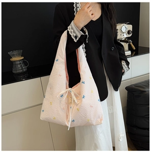 Gros plan d'un sac en seersucker rose avec broderies nœuds et ruban blanc décoratif