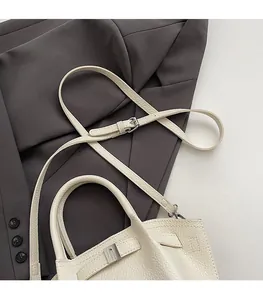 Close-up of minimalist cream white bucket bag with pebble leather and silver buckle detail