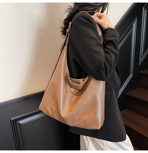 Detail shot of a brown leather tote with signature triangle plaque in professional use