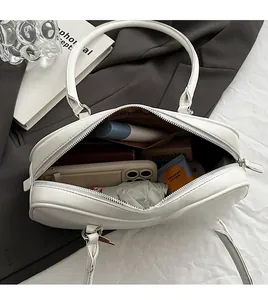 Top view of white underarm bag showing interior space with phone and cosmetics