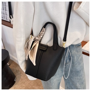 Close-up of black pebble leather bucket bag featuring decorative silk scarf handle wrap