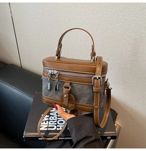 Close-up of vintage box bag featuring brown leather and grey denim stitching detail