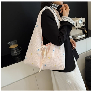 Vue détaillée d'un sac cabas rose matelassé avec broderies de nœuds colorés et attaches
