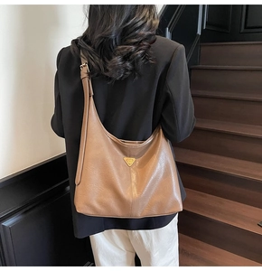 Close-up of brown hobo tote bag with gold triangle logo on textured synthetic leather