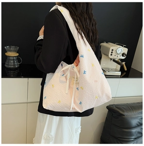 Gros plan sur un sac cabas matelassé rose avec broderies papillons et nœud sur le côté