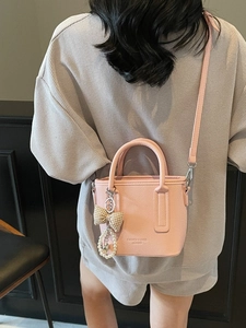Pink lychee grain leather mini bucket bag with elegant heart pendant and shoulder strap