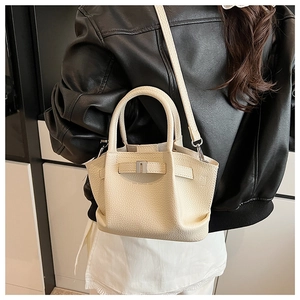 Close-up of lychee grain cream bucket bag with metal buckle on a black leather jacket