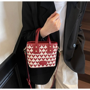 Detail of red and white heart knit handbag with leather handles and gold metal clips