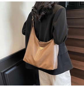 Detailed view of the tan soft leather hobo bag with a metallic triangle logo plate
