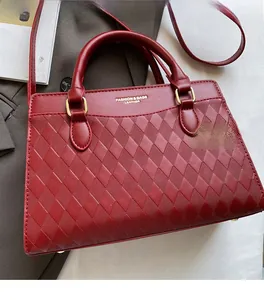 Detail of burgundy quilted leather tote featuring gold lettering and round handles