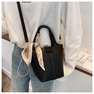 Detail of black litchi grain bucket bag with decorative silk scarf and adjustable strap