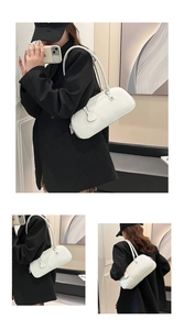 Detail view of white matte leather underarm bag with long strap and side pendant