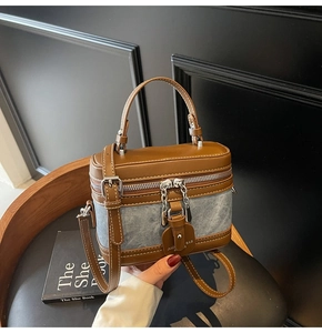 Détail de couture contrastée en cuir marron et denim bleu avec fermeture éclair métal