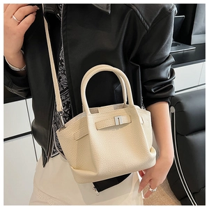 Close-up of cream leather bucket bag with metal buckle and detachable shoulder strap