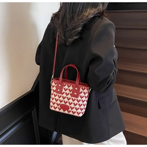 Model wearing a red heart-patterned bridal handbag with leather straps and gold studs