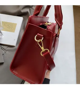 Close-up of wine red leather handbag featuring gold metal hardware and wave pattern texture