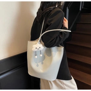 Detail of light blue litchi grain tote bag with white plush cloud charm on shoulder