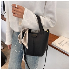 Detail of black lychee grain leather bucket bag with decorative scarf and shoulder strap