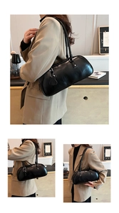 Detail of black glossy baguette bag featuring double handles and heart pendant decoration