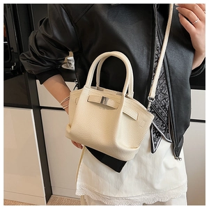 Detail of cream white leather bucket bag with decorative scarf and pebble grain texture