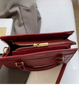Detail view of wine red leather handbag featuring checkered texture and golden zipper