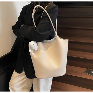 Close-up of cream lychee texture bucket bag with a cute white cloud plush pendant