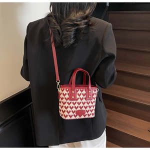 Detail of red and white knitted heart bucket bag with leather strap on model