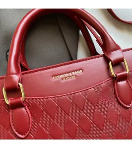 Detail of red leather bag with diamond lattice embossing and golden fashion lettering