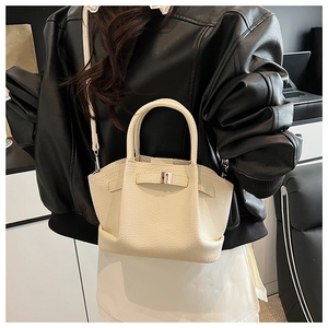 Detail showing beige lychee grain leather texture and metallic buckle on a bucket bag