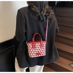 Detail of red heart patterns on cream fabric mini tote bag with red leather handles