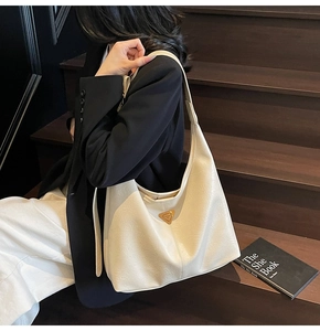 Detail of cream white textured tote bag with golden triangle plaque and wide strap