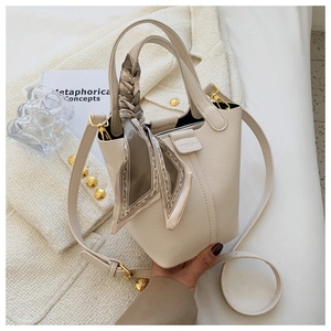 Detail of cream bucket bag with lychee texture, silk scarf handle and golden hardware