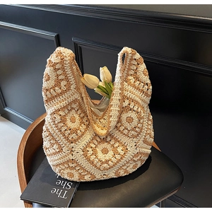 Detailed close-up of Bohemian crochet granny square shoulder bag on a vintage wooden chair