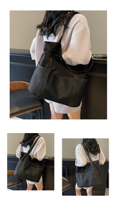 Detalle del bolso tote negro de gran capacidad con bolsillos de malla y asas dobles