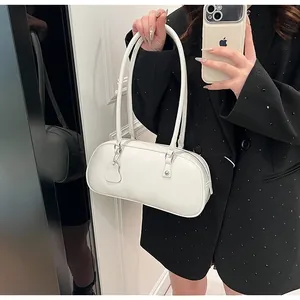 Mirror selfie showing the white leather cylindrical underarm bag with a long shoulder strap
