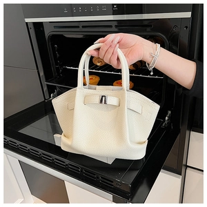 Detail of cream lychee pattern leather bucket bag with silver buckle and handles