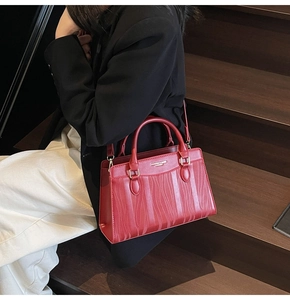 Close-up of a red wedding tote bag featuring vertical wave embossing and metallic logo detail