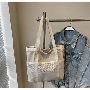 Detalle de bolso tote de lona con bolsillos de malla y asas de tejido reforzado