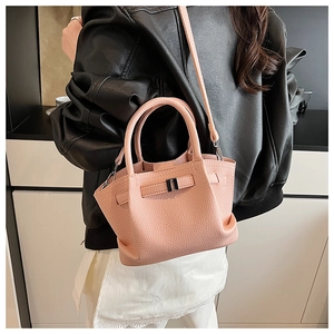 Close-up of pink litchi grain leather bucket bag shown on model with shoulder strap