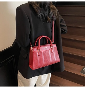 Detail of red wedding tote bag featuring a textured wavy pattern and gold metal hardware