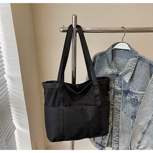 Detalle del bolso tote negro con fondo de malla transpirable y lona en una percha de metal