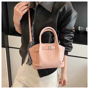 Detail of pink bucket bag with lychee texture and silver buckle on black leather jacket