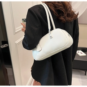 Close-up of white leather shoulder bag with sleek strap shown on model in black blazer