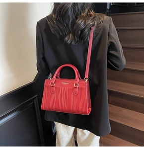 Detail of red bridal leather tote with wave texture and gold hardware on stairs