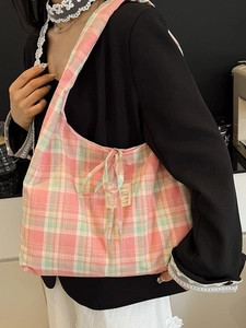 Sac fourre-tout à carreaux rose et vert avec nœud porté par un mannequin en veste noire