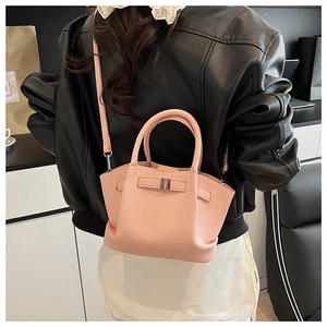 Detailed side view of a pink pebbled leather bucket bag styled on a female model