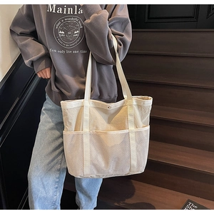 Vista lateral detallada del bolso tote de lona blanco roto con bolsillo de malla