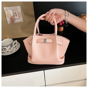 Close-up of pink lychee grain leather bucket bag with silver buckle in hand