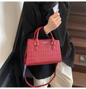 Detail of red quilted tote bag with gold hardware and adjustable strap shown on model