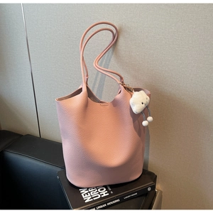 Close-up of pink litchi grain leather tote bag with white cloud plush pendant